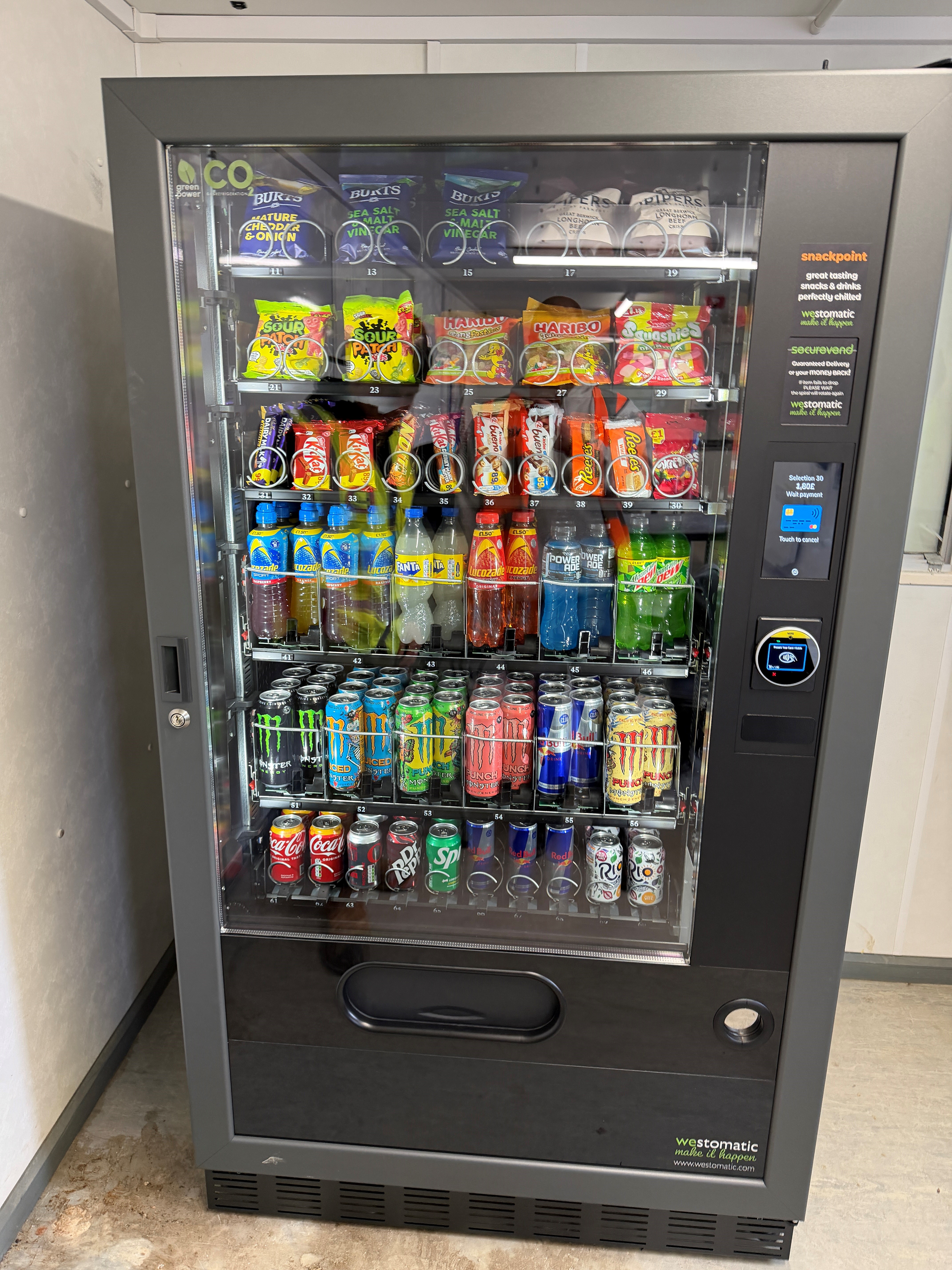 A Venom Vending snack and drinks machine stocked with crisps, sweets, chocolate, bottled drinks and cans, with a contactless payment terminal.